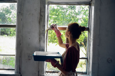 Side view of woman standing by window