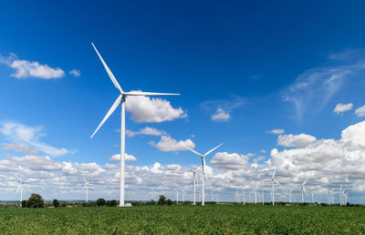 Windmills for electric power production in cassava field on blue sky 