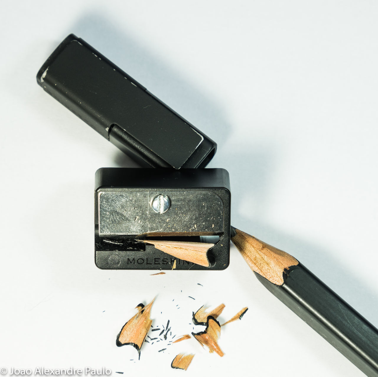 table, still life, high angle view, no people, pencil sharpener, indoors, close-up, white background, pencil shavings, day