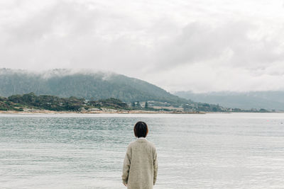 Rear view of woman looking at sea against mountains