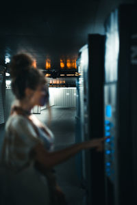 Rear view of woman standing against illuminated building