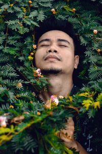 Close-up of man with eyes closed by plants