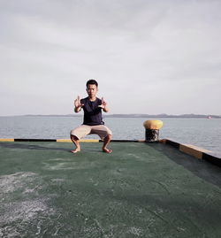 Full length of man jumping on sea against sky