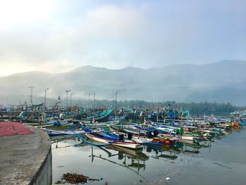 Boats moored at harbor against sky