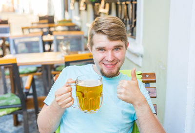 Portrait of smiling man holding beer glass at bar