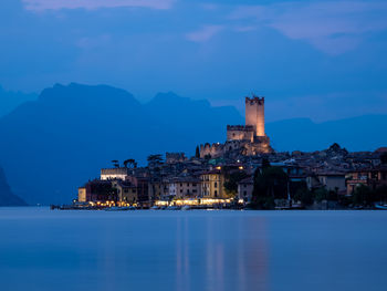 Buildings by sea against sky