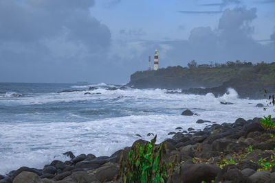 Lighthouse by sea against sky