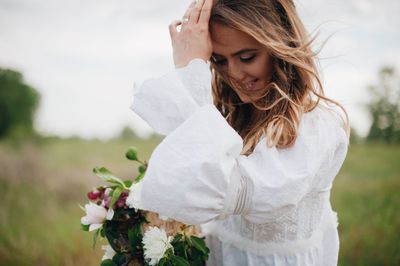 Bride holding bouquet while standing on field