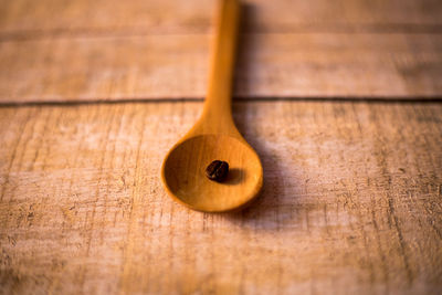 Close-up of roasted coffee bean in wooden spoon on table