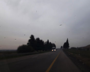 Road seen through wet glass during rainy season