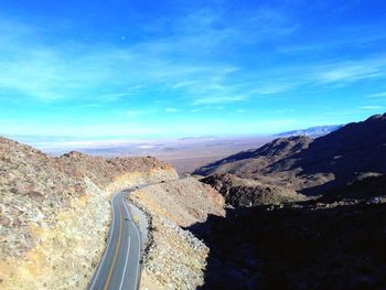 High angle view of road amidst landscape against blue sky