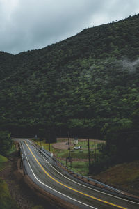 Road amidst trees on landscape against sky