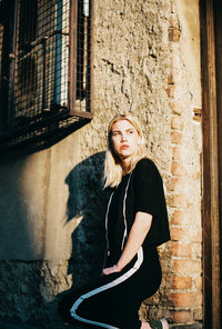 Low angle view of young woman standing by wall