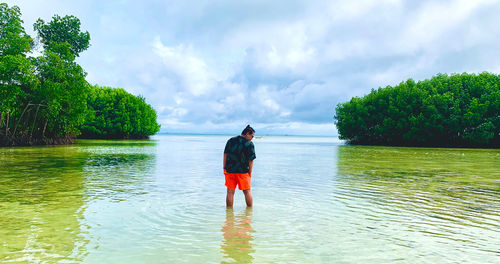 Rear view of a guy standing with mangroves in the background