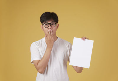 Portrait of mid adult man standing against yellow background