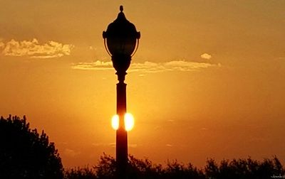 Low angle view of illuminated street light against orange sky