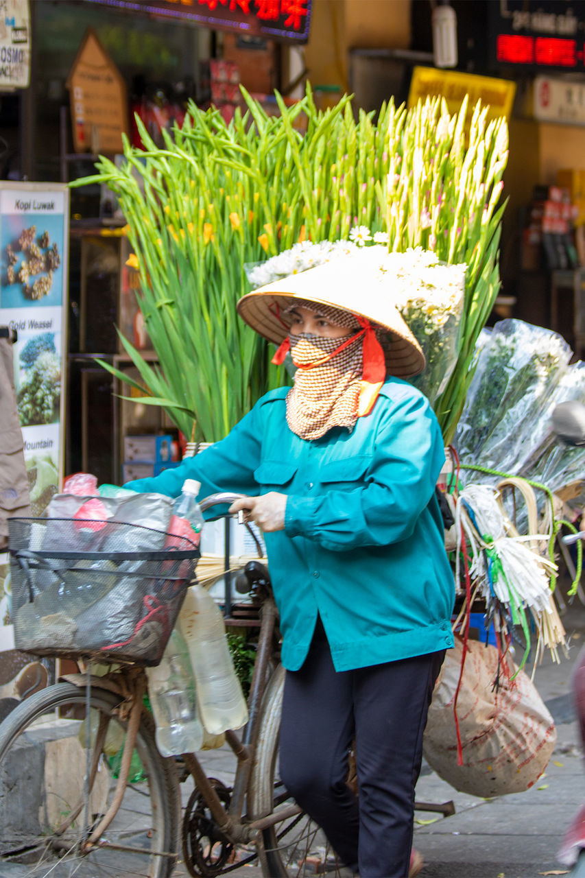 MIDSECTION OF WOMAN WITH BICYCLE IN BASKET AT MARKET STALL