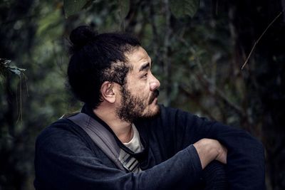 Young man looking away in forest