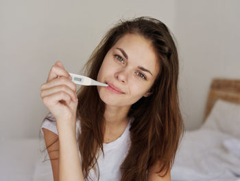 Portrait of beautiful young woman holding bed at home