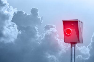 Low angle view of speed camera against cloudy sky