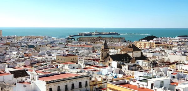 High angle view of townscape by sea against clear sky