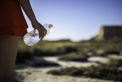 Midsection of woman holding glass bottle
