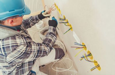 High angle view of electrician installing wires on wall