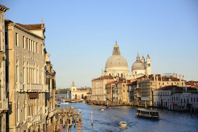 Boats in canal amidst city against sky