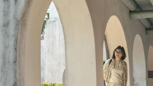 Portrait of woman standing against built structure