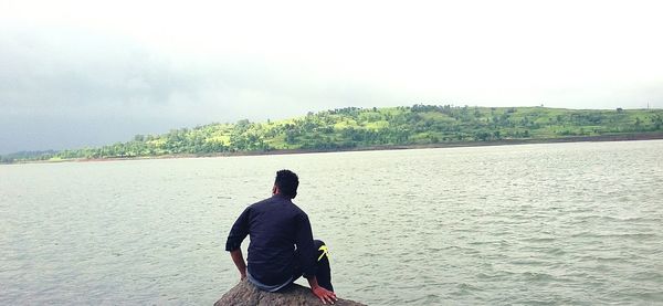 Rear view of man standing on lake