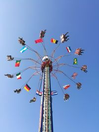 Low angle view of ferris wheel against clear blue sky