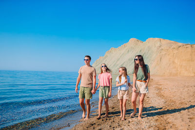 People standing at beach against clear blue sky