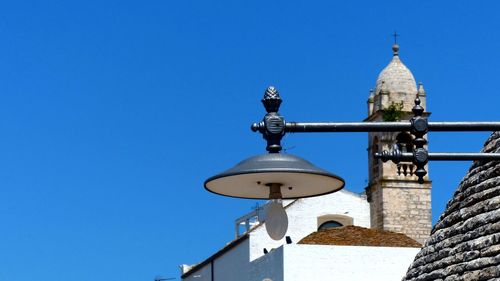 Low angle view of clock tower amidst buildings against clear blue sky