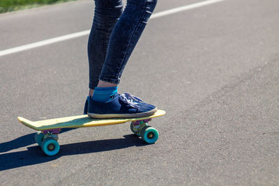 Low section of woman skateboarding on road