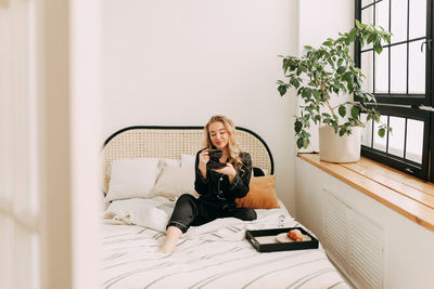 Portrait of woman sitting on bed at home