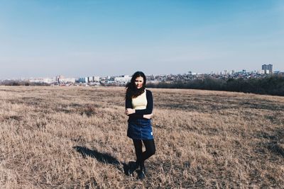 Portrait of young woman standing on field against sky