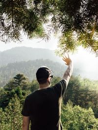 Rear view of man standing against trees