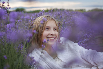 Portrait of smiling woman with purple flowers on land