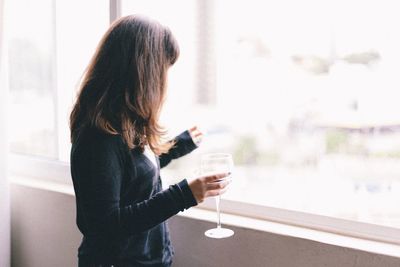 Woman holding wineglass by window