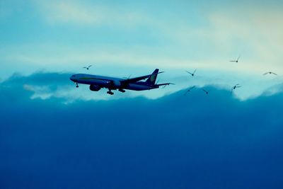 Low angle view of silhouette airplane against sky at dusk