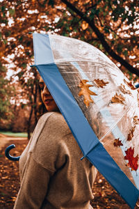 Girl holding transparent umbrella in the autumn street in rainy day. woman under transparent 