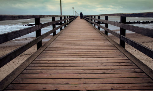 Wooden pier leading towards sea against sky