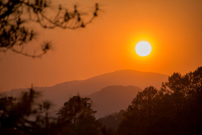 Scenic view of silhouette mountains against orange sky