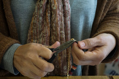 Midsection of woman repairing gold chain in store