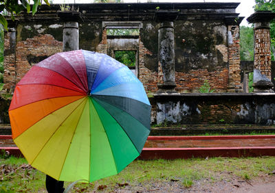 Multi colored umbrella against trees and building