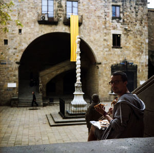 Portrait of young man eating pizza while sitting on steps in building