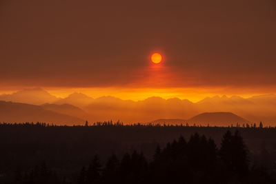 Scenic view of silhouette mountains against orange wildfire smoke sky