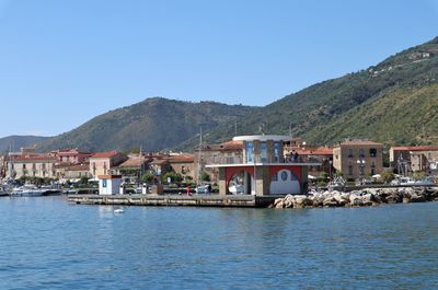 Buildings by sea against clear sky