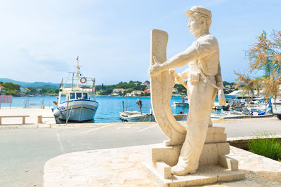 Statue by sea against sky