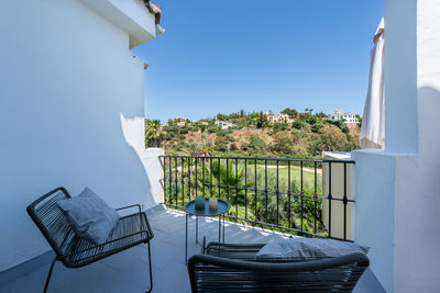 Empty chairs and tables at beach against sky